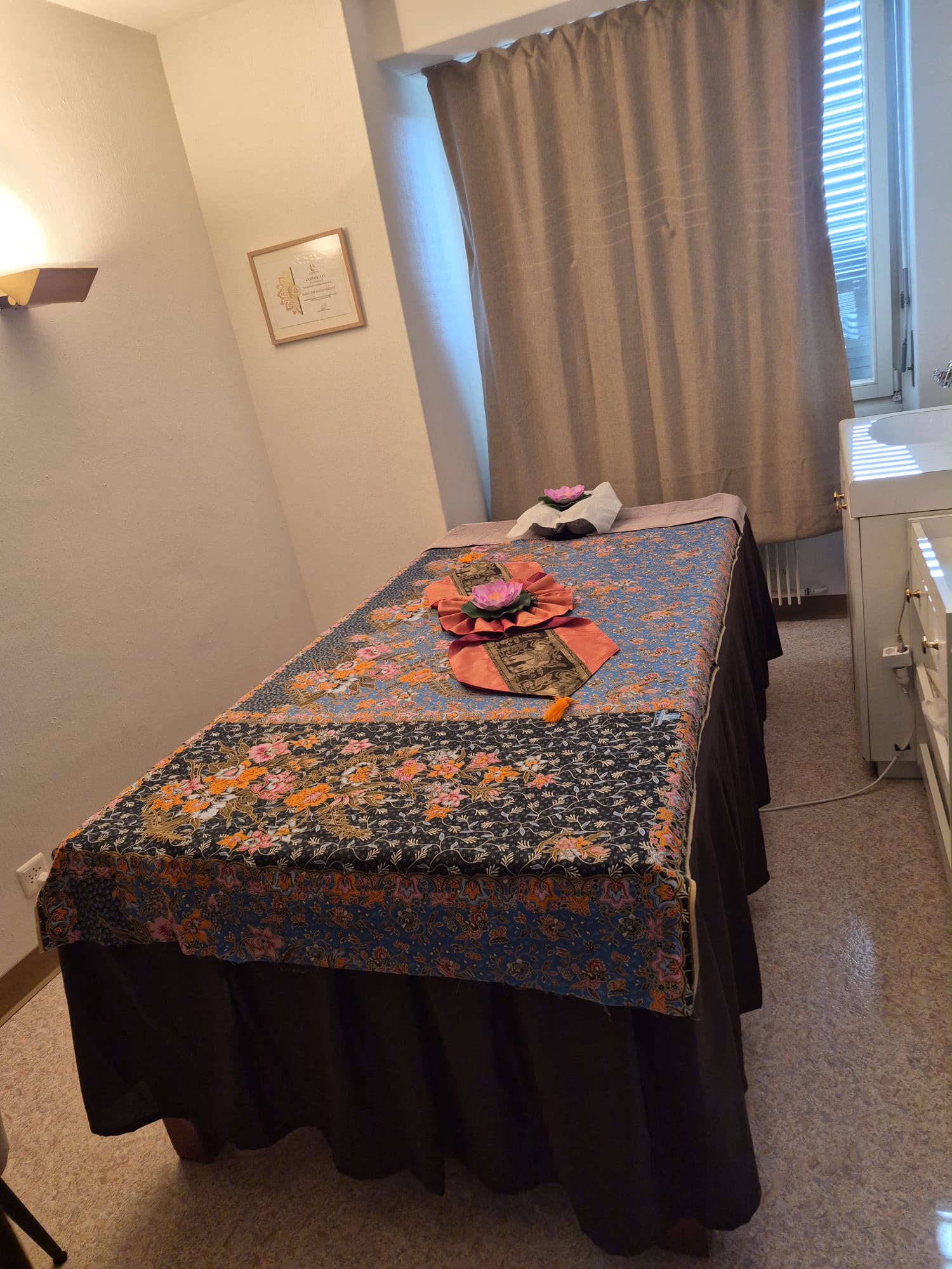 Massageliege mit traditionellem Thai Stoff und Lotusblüten