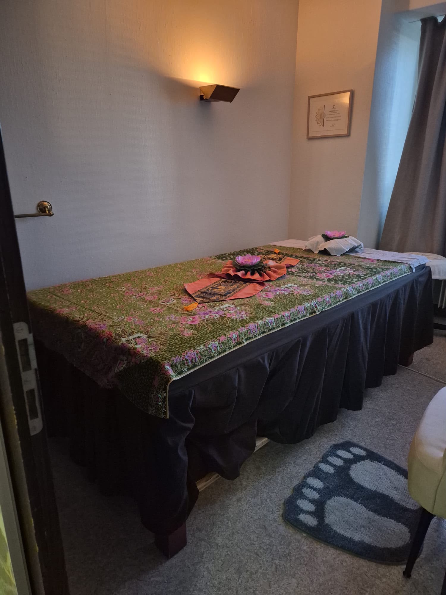 Behandlungsraum mit Massageliege, Lotusblüte und Zertifikat