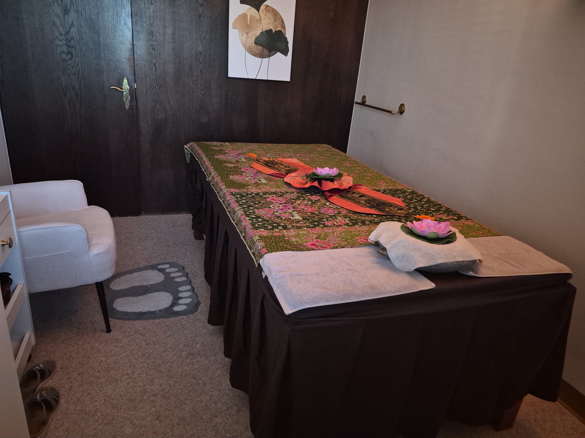 Ruhiger Behandlungsraum mit dunkler Holzwand und Massageliege